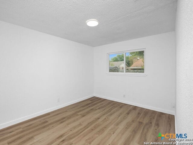 spare room with a textured ceiling and hardwood / wood-style flooring