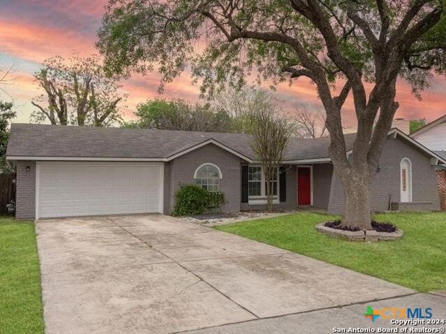 single story home with a garage and a yard