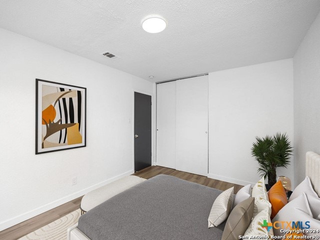 bedroom with a closet, hardwood / wood-style floors, and a textured ceiling