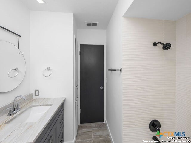 bathroom with vanity, tile patterned floors, and a tile shower