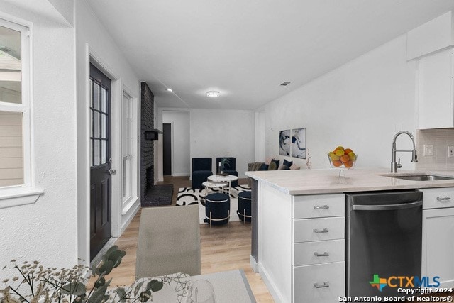 kitchen featuring backsplash, sink, light hardwood / wood-style floors, white cabinets, and dishwasher