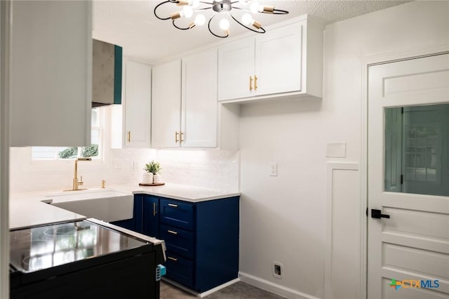1004 Buena Vista Ave, Victoria, TX 77901 - kitchen featuring blue cabinetry, tasteful backsplash, a chandelier, a sink, and white cabinets