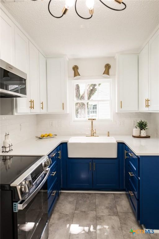 1004 Buena Vista Ave, Victoria, TX 77901 - kitchen featuring appliances with stainless steel finishes, blue cabinetry, a sink, decorative backsplash, and a textured ceiling