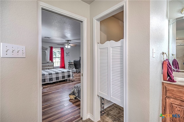 hallway with a textured ceiling and dark hardwood / wood-style flooring