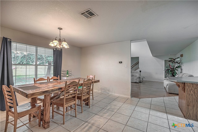 dining space with light tile patterned flooring, a textured ceiling, and an inviting chandelier