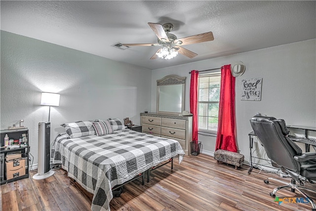 bedroom with wood-type flooring, ceiling fan, and a textured ceiling