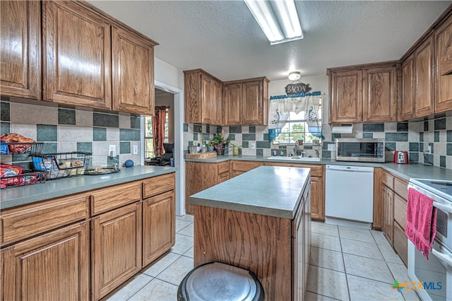 kitchen with white dishwasher, light tile patterned floors, stove, sink, and a kitchen island