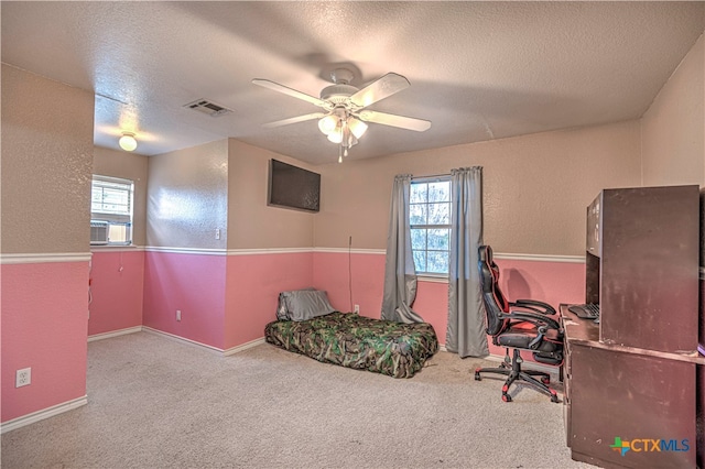 interior space with a wealth of natural light, ceiling fan, a textured ceiling, and carpet flooring