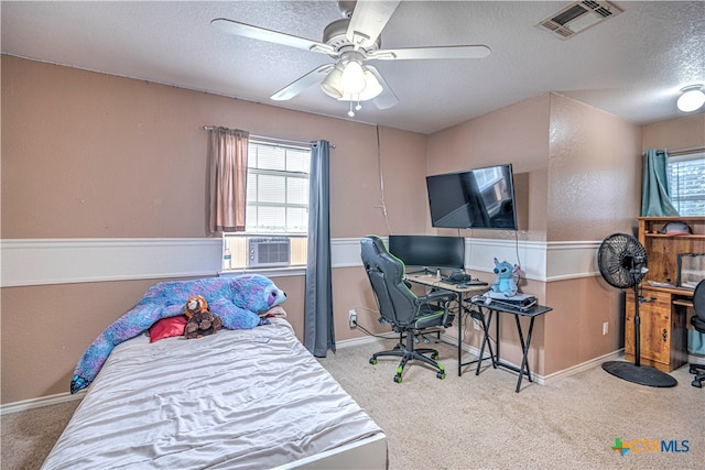 bedroom with cooling unit, a textured ceiling, light colored carpet, and ceiling fan