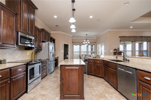 kitchen with appliances with stainless steel finishes, a center island, decorative light fixtures, and sink