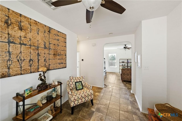 living area with arched walkways, visible vents, ceiling fan, and baseboards