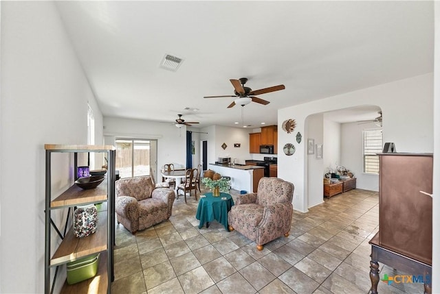 living area with arched walkways, plenty of natural light, and visible vents