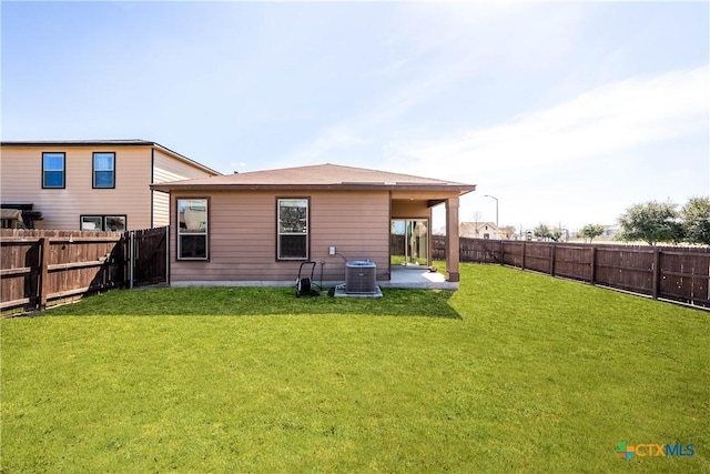 rear view of house with a fenced backyard, cooling unit, a lawn, and a patio