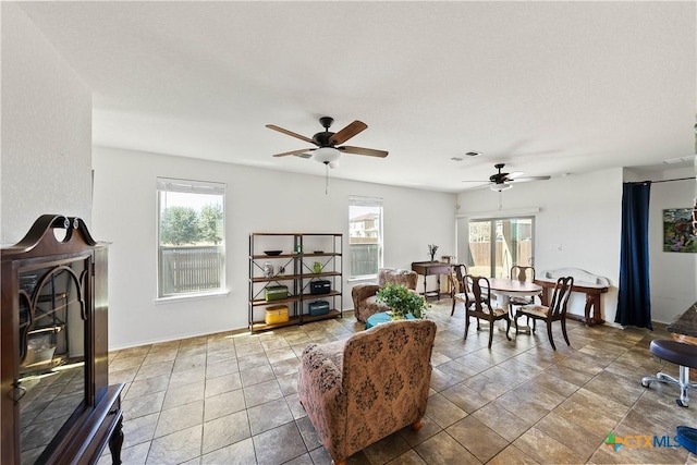 living area featuring a ceiling fan, a wealth of natural light, visible vents, and a fireplace