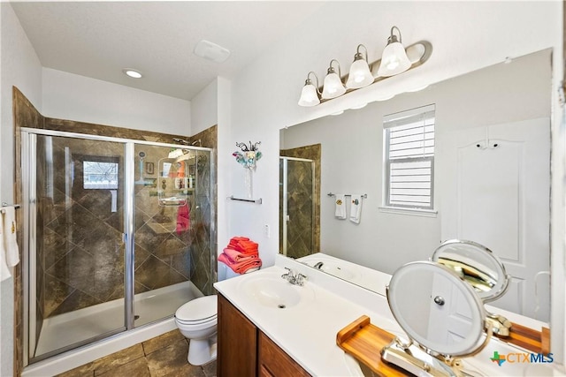 bathroom with vanity, a shower stall, and toilet