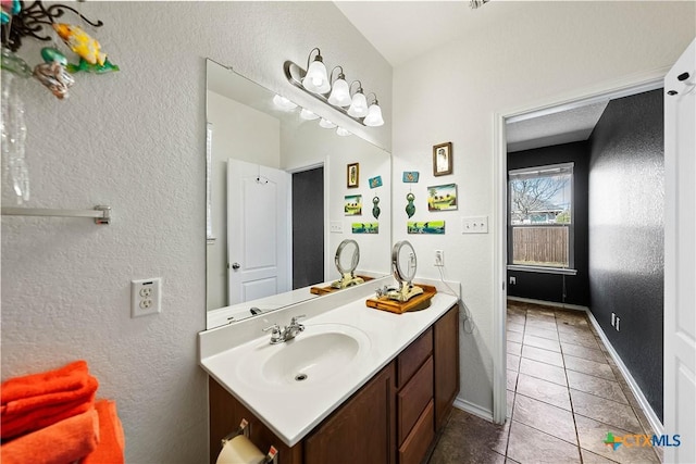 bathroom featuring baseboards, a textured wall, vanity, and tile patterned floors