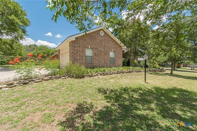 127 Maple Dr, Mountain City, TX 78610 - view of property exterior with a garage, a lawn, and brick siding