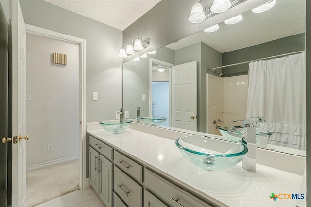 127 Maple Dr, Mountain City, TX 78610 - bathroom with a textured ceiling, double vanity, a shower with shower curtain, and tile patterned floors