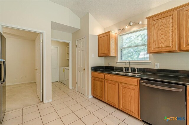 127 Maple Dr, Mountain City, TX 78610 - kitchen featuring appliances with stainless steel finishes, dark countertops, washing machine and dryer, light tile patterned flooring, and a textured ceiling