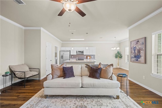 living area featuring ceiling fan with notable chandelier, visible vents, baseboards, dark wood finished floors, and crown molding