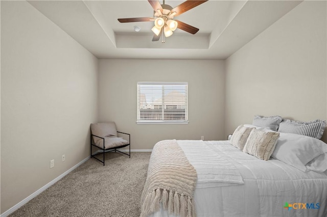 bedroom featuring carpet floors, baseboards, a raised ceiling, and a ceiling fan