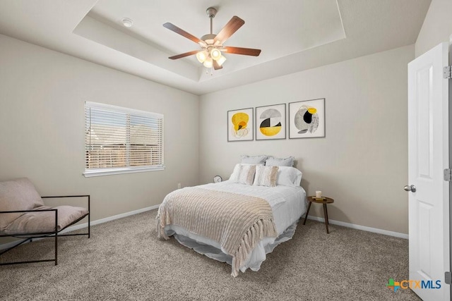 carpeted bedroom with a raised ceiling, ceiling fan, and baseboards