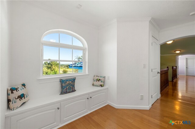 hallway featuring light wood-type flooring and crown molding