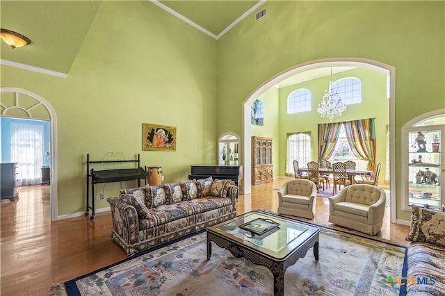 living room featuring high vaulted ceiling, hardwood / wood-style flooring, crown molding, and plenty of natural light