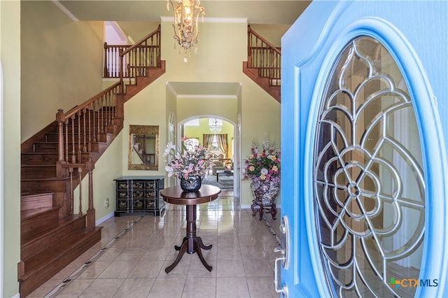 foyer entrance featuring a high ceiling, light tile patterned floors, and an inviting chandelier