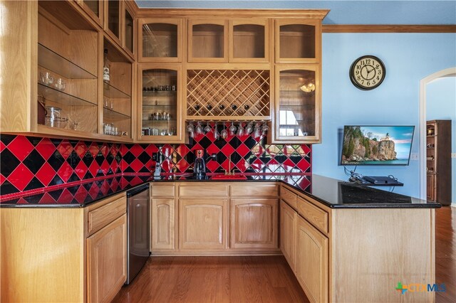 bar featuring decorative backsplash, light hardwood / wood-style flooring, dark stone counters, and crown molding