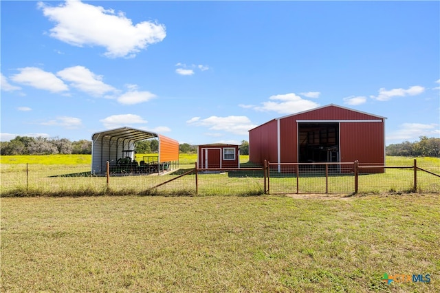 view of yard with a rural view, a carport, and an outdoor structure