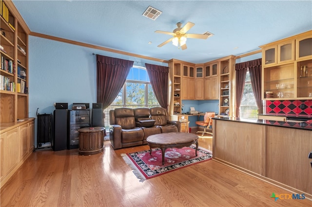 living room with ornamental molding, light wood-type flooring, ceiling fan, and built in desk