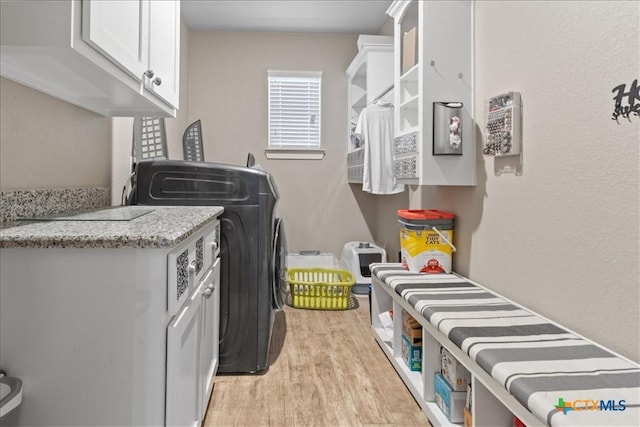 laundry area featuring washer / clothes dryer, cabinets, and light hardwood / wood-style floors