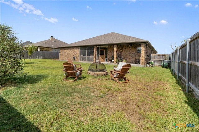 back of house with a yard and a fire pit