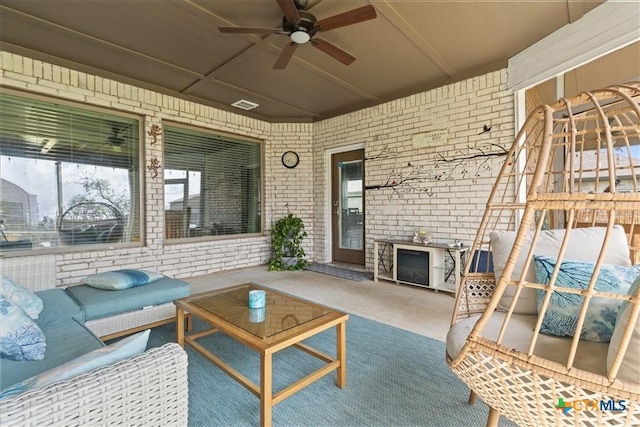 exterior space featuring ceiling fan and brick wall