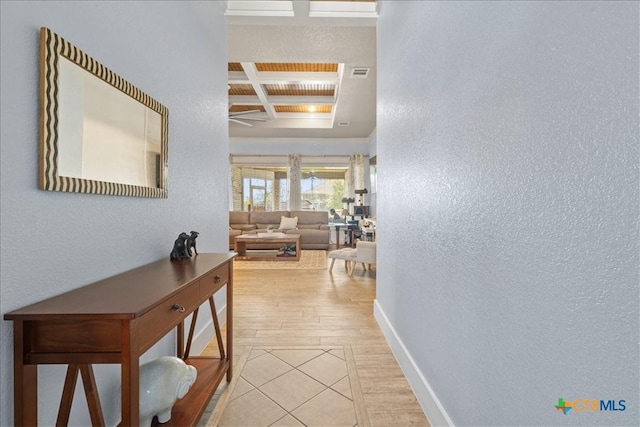 corridor featuring coffered ceiling, beam ceiling, and light hardwood / wood-style flooring