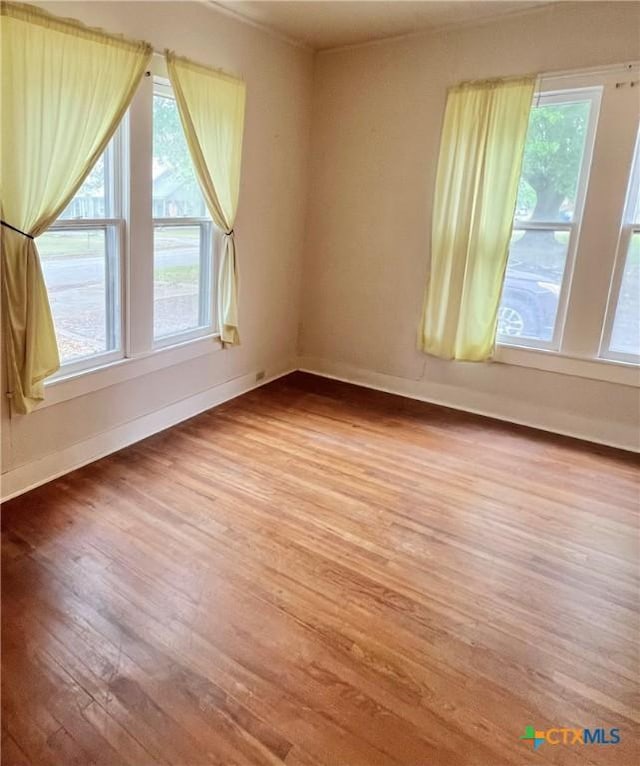 spare room featuring wood finished floors and baseboards