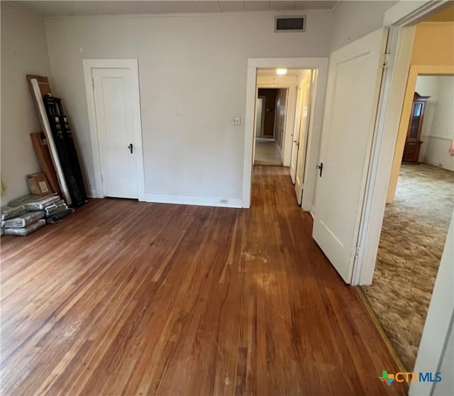unfurnished room with wood finished floors and visible vents