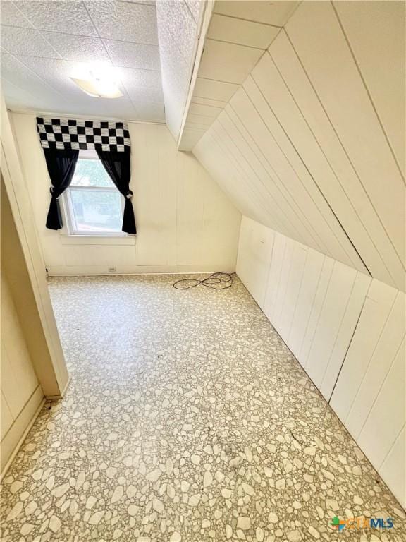 additional living space featuring wooden walls and lofted ceiling