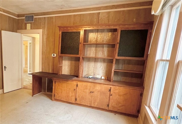 interior space with ornamental molding, visible vents, and wood walls