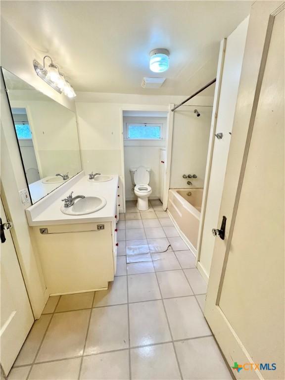 bathroom with tile patterned floors, toilet, double vanity, and a sink