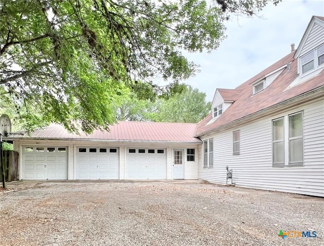 exterior space with a garage, driveway, and metal roof