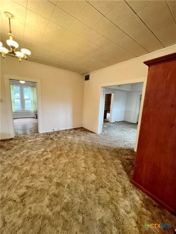 carpeted empty room featuring visible vents and a notable chandelier