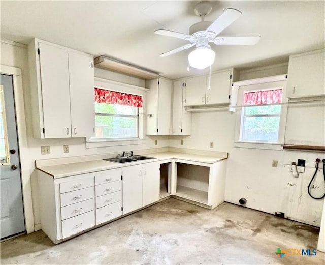 kitchen featuring concrete floors, a healthy amount of sunlight, white cabinetry, and a sink