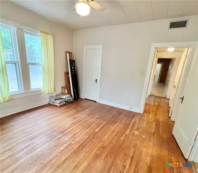 spare room with light wood finished floors, a ceiling fan, visible vents, and baseboards