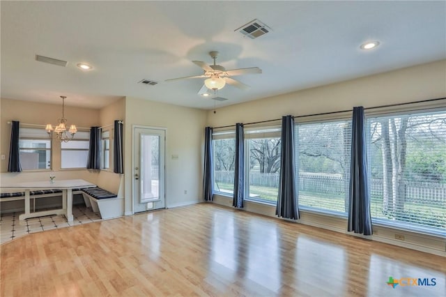 living room featuring ceiling fan with notable chandelier and light hardwood / wood-style flooring