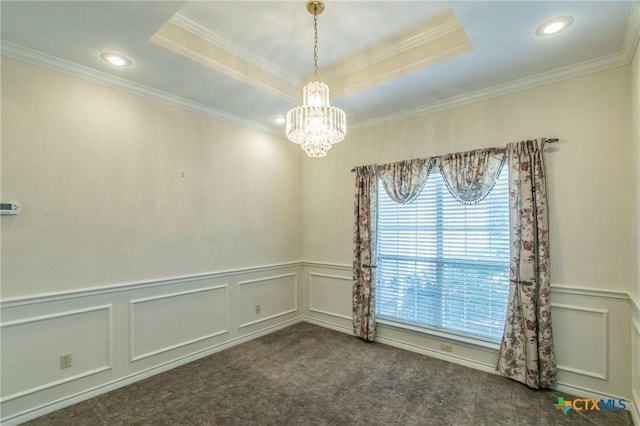 carpeted empty room featuring a notable chandelier, a tray ceiling, and crown molding