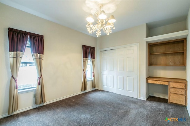 unfurnished bedroom featuring an inviting chandelier, a closet, and dark carpet