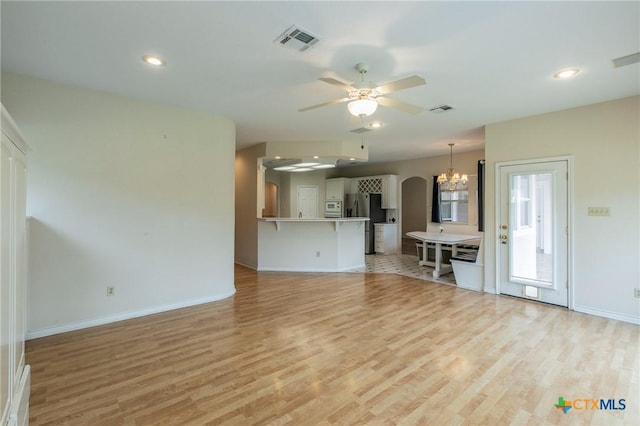 unfurnished living room with ceiling fan with notable chandelier and light wood-type flooring