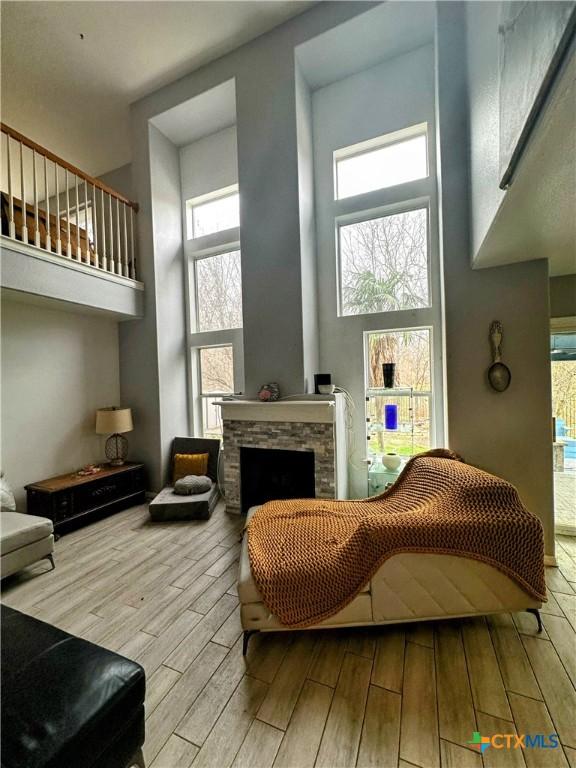 living area with a towering ceiling, a fireplace, and light wood-type flooring